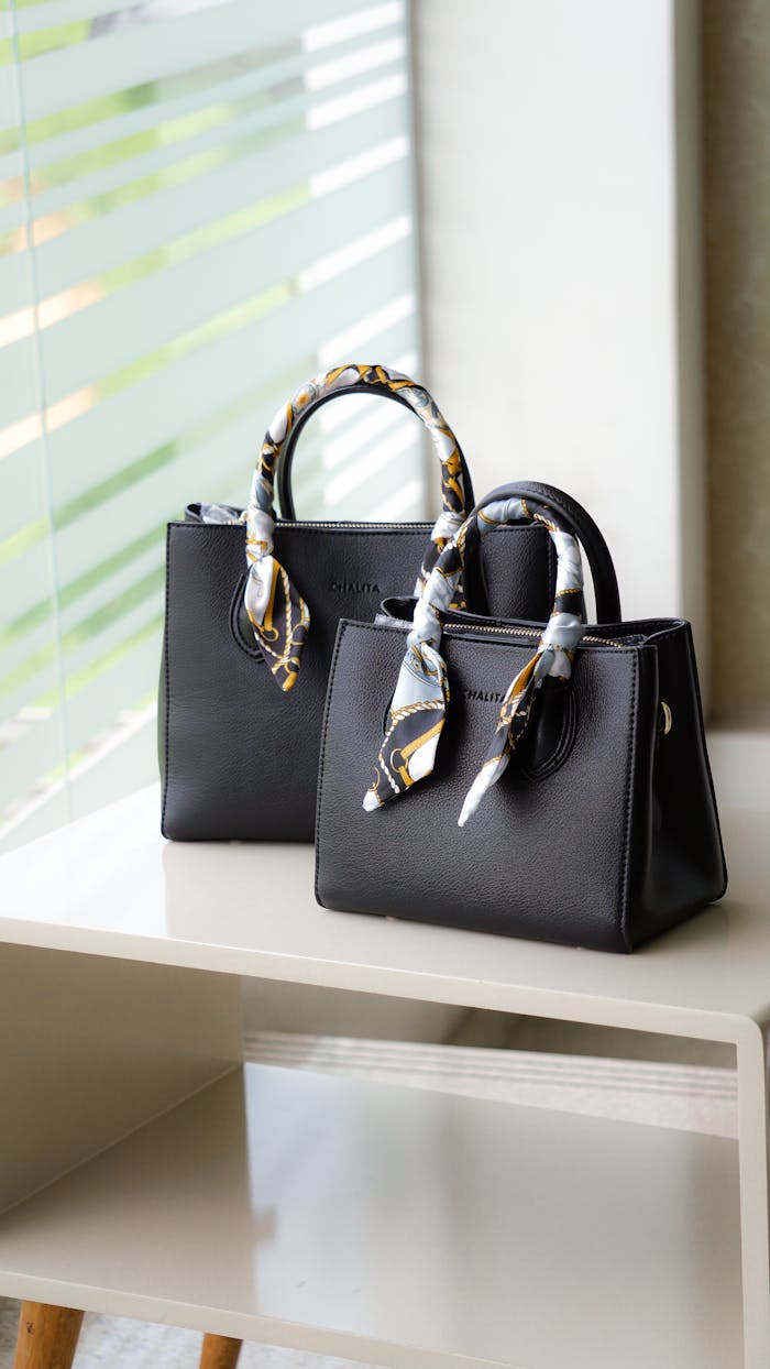 services-04 Stylish black leather handbag with decorative handles on a minimalist shelf.
