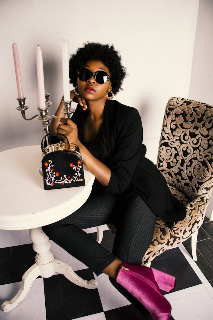 who-we-are Fashion-forward African American woman posing indoors with accessories, exuding elegance and style.
